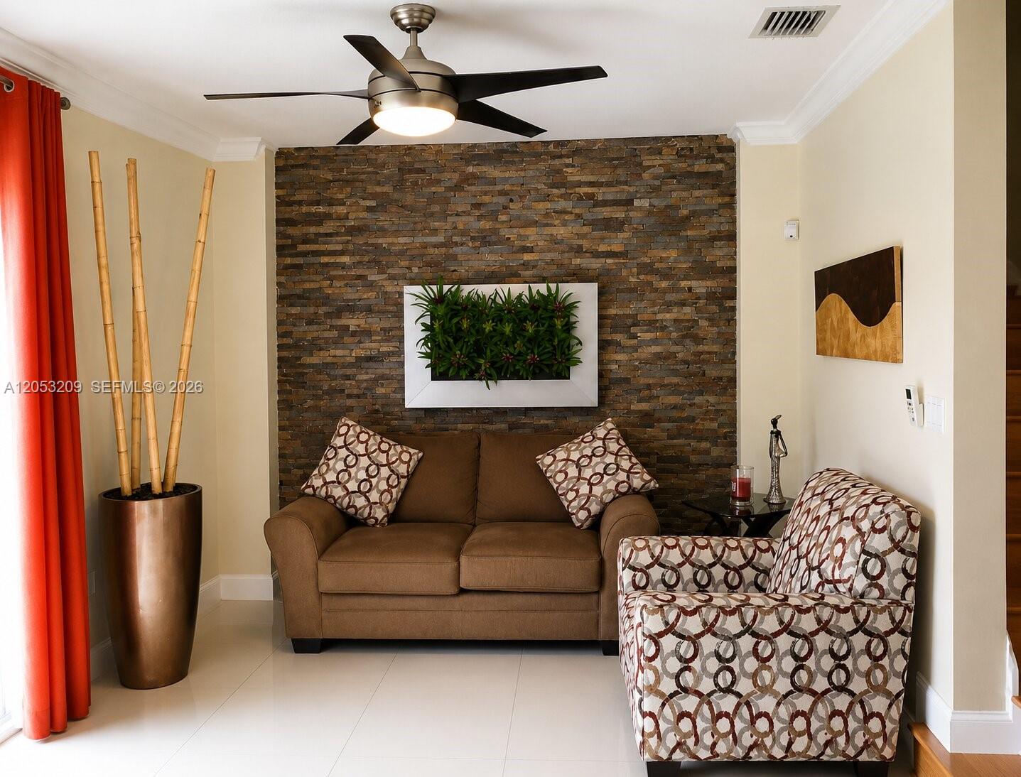 A living room features a stone accent wall, a brown sofa, and a patterned armchair — 12945 SW 29th St, Miramar FL 33027, MIRAMAR, FL