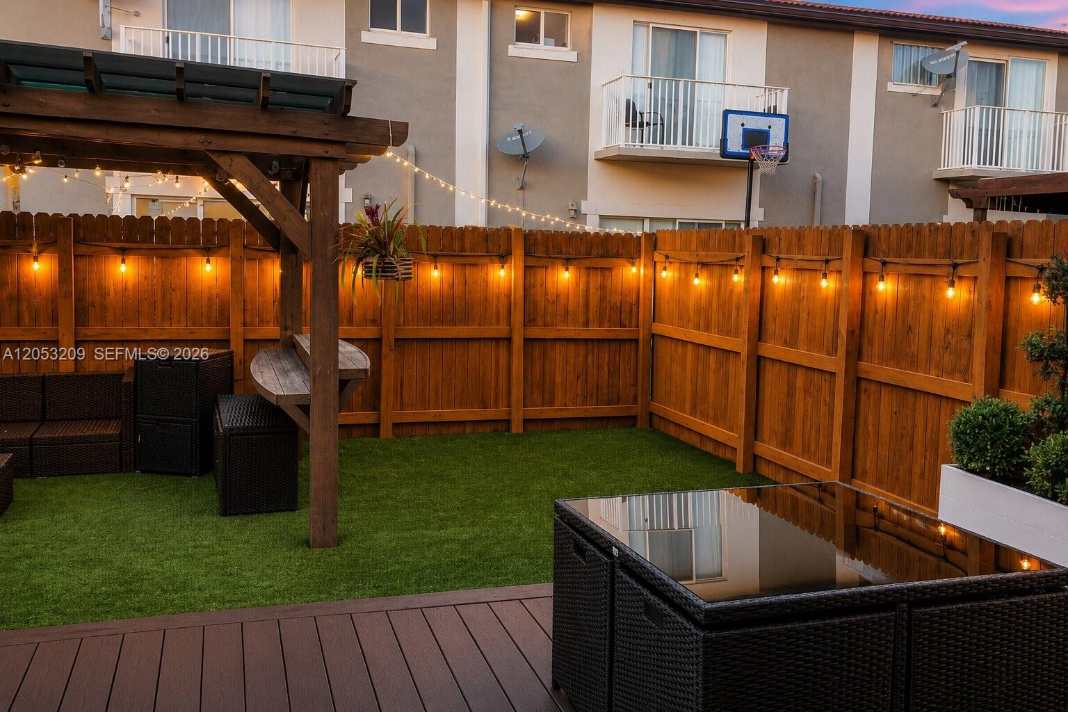 A backyard patio features a wooden pergola, artificial turf, a wooden fence, and string lights — 12945 SW 29th St, Miramar FL 33027, MIRAMAR, FL