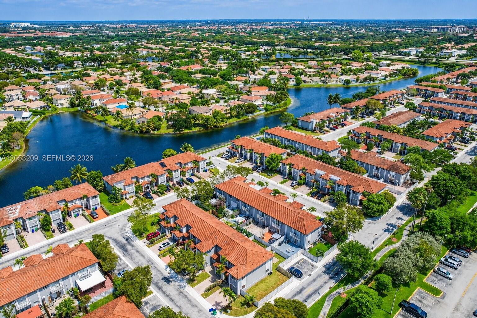 An aerial view shows multiple residential townhome buildings with red tile roofs near a lake — 12945 SW 29th St, Miramar FL 33027, MIRAMAR, FL