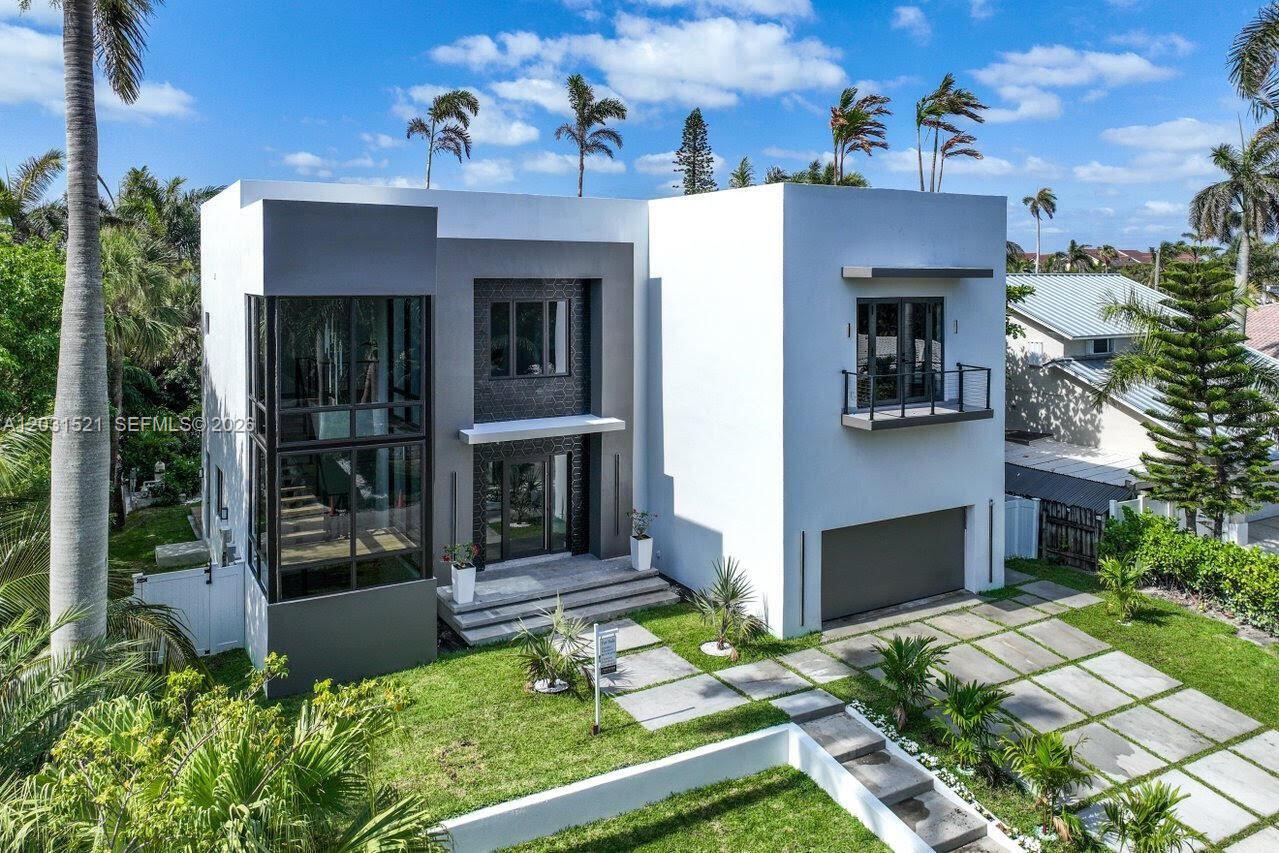 A modern two-story house features a glass-walled entryway, a balcony, and a paved driveway — 638 Lakeside Harbor, Boynton Beach FL 33435, BOYNTON BEACH, FL