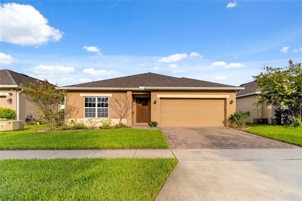 A single-story house with a tan stucco exterior, a brown roof, and a two-car garage — 125 WILLIAMSON DRIVE, DAVENPORT, FL