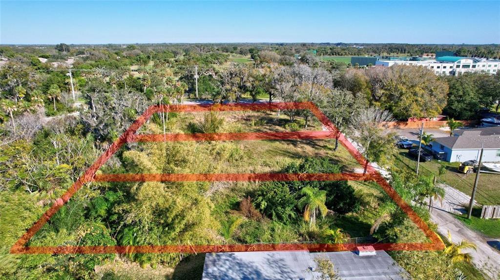 An aerial view shows a vacant, rectangular lot outlined in red, surrounded by trees and vegetation — 2619 16TH AVENUE DRIVE E, BRADENTON, FL