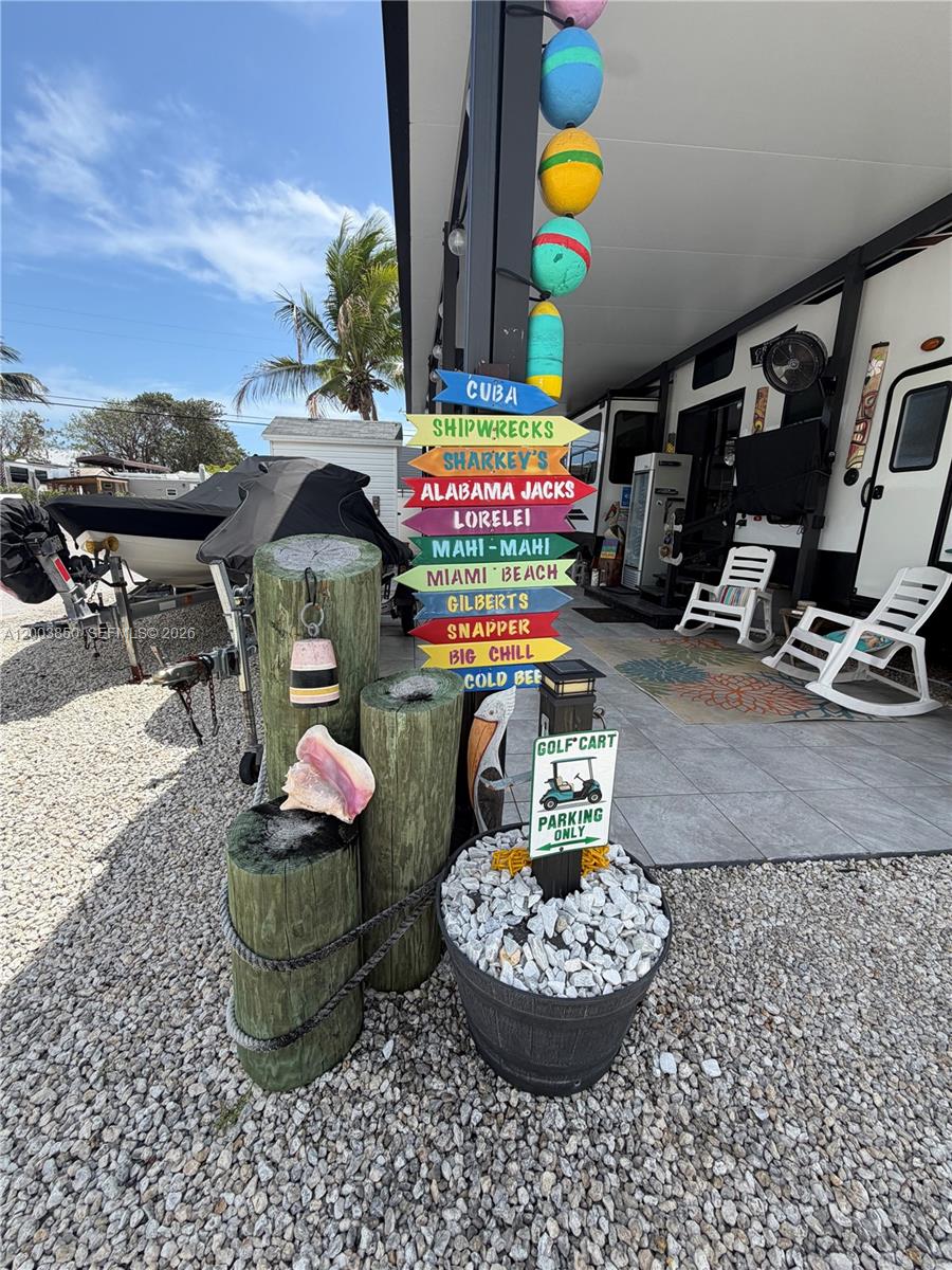 A decorative signpost with directional arrows stands on a gravel lot beside a parked RV — 325 Calusa St Lot 345, Key Largo FL 33037, KEY LARGO, FL