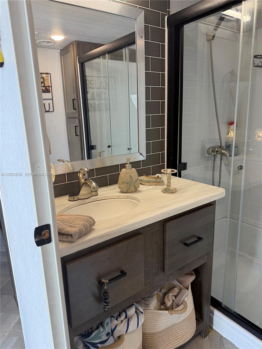 A bathroom features a wood vanity, a light-colored countertop, a mirror, and a glass shower — 325 Calusa St Lot 345, Key Largo FL 33037, KEY LARGO, FL