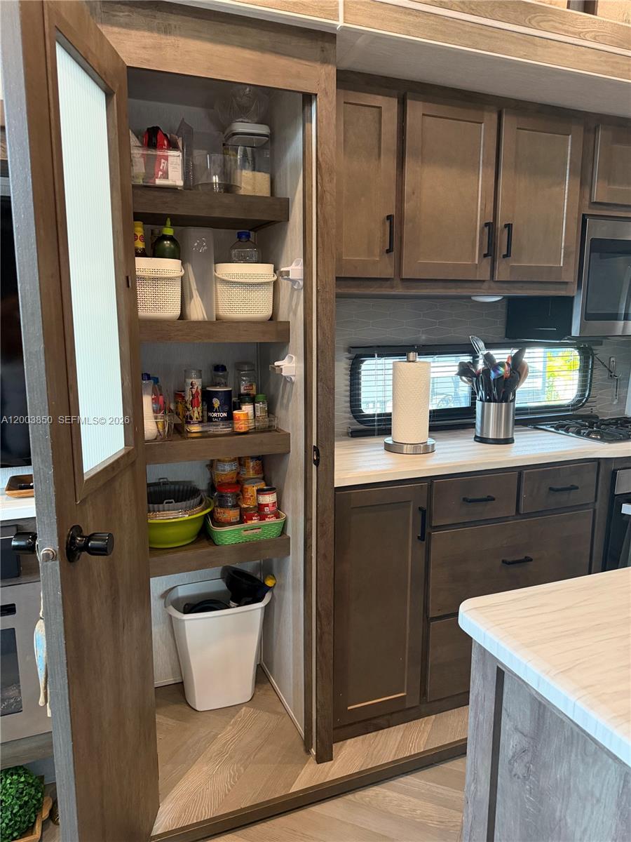 A kitchen features a tall pantry with open shelving next to wooden cabinets and countertops — 325 Calusa St Lot 345, Key Largo FL 33037, KEY LARGO, FL