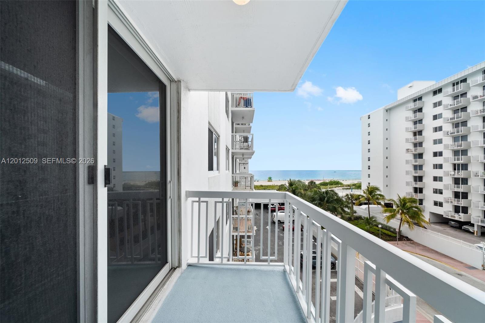 A balcony with a white metal railing overlooks a parking lot and the ocean — 401 Ocean Dr # 509, Miami Beach FL 33139, MIAMI BEACH, FL