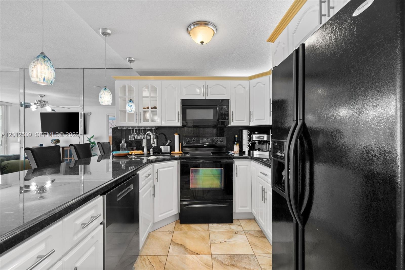 A kitchen features white cabinets, black appliances, dark countertops, and light-colored tile flooring — 401 Ocean Dr # 509, Miami Beach FL 33139, MIAMI BEACH, FL