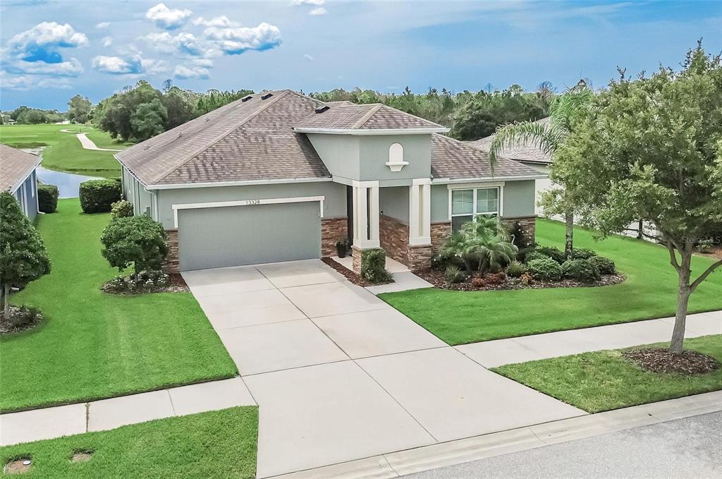 A single-story house with a gray exterior, stone accents, and a two-car garage — 13328 PALMERA VISTA DRIVE, RIVERVIEW, FL