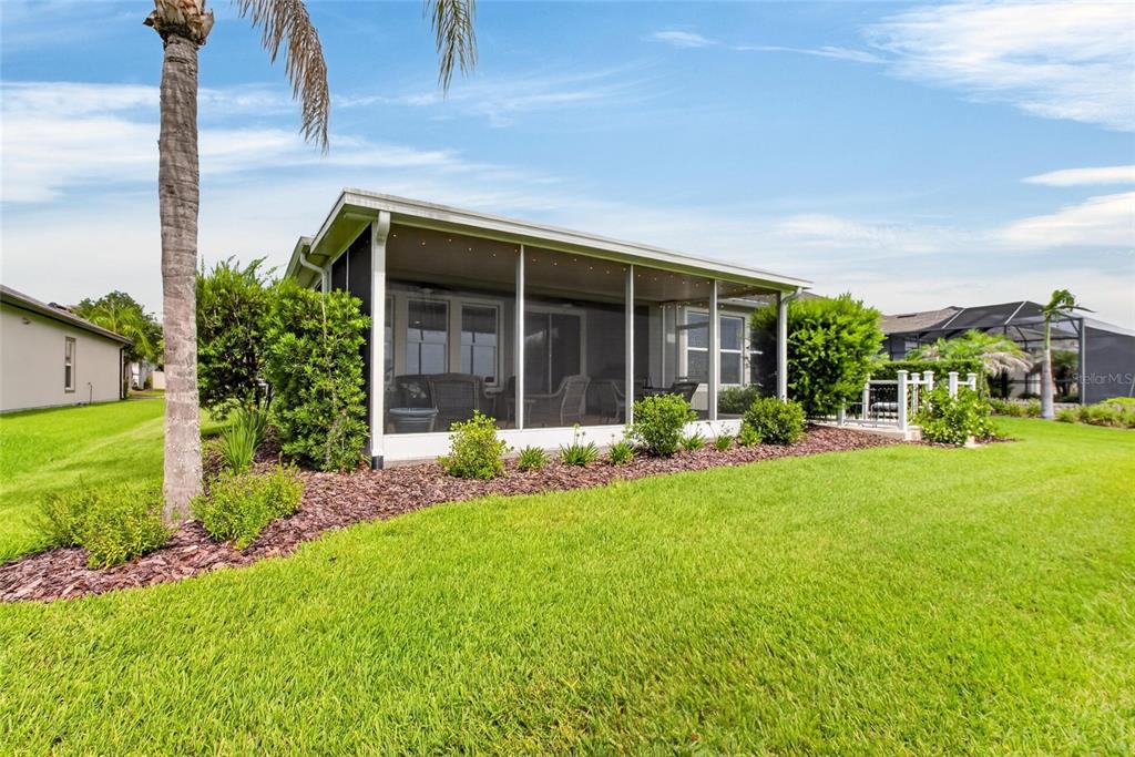 A screened-in patio overlooks a grassy backyard with landscaping and a palm tree — 13328 PALMERA VISTA DRIVE, RIVERVIEW, FL