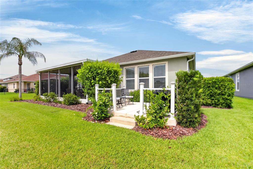 A backyard view of a house with a screened-in porch and a small patio — 13328 PALMERA VISTA DRIVE, RIVERVIEW, FL