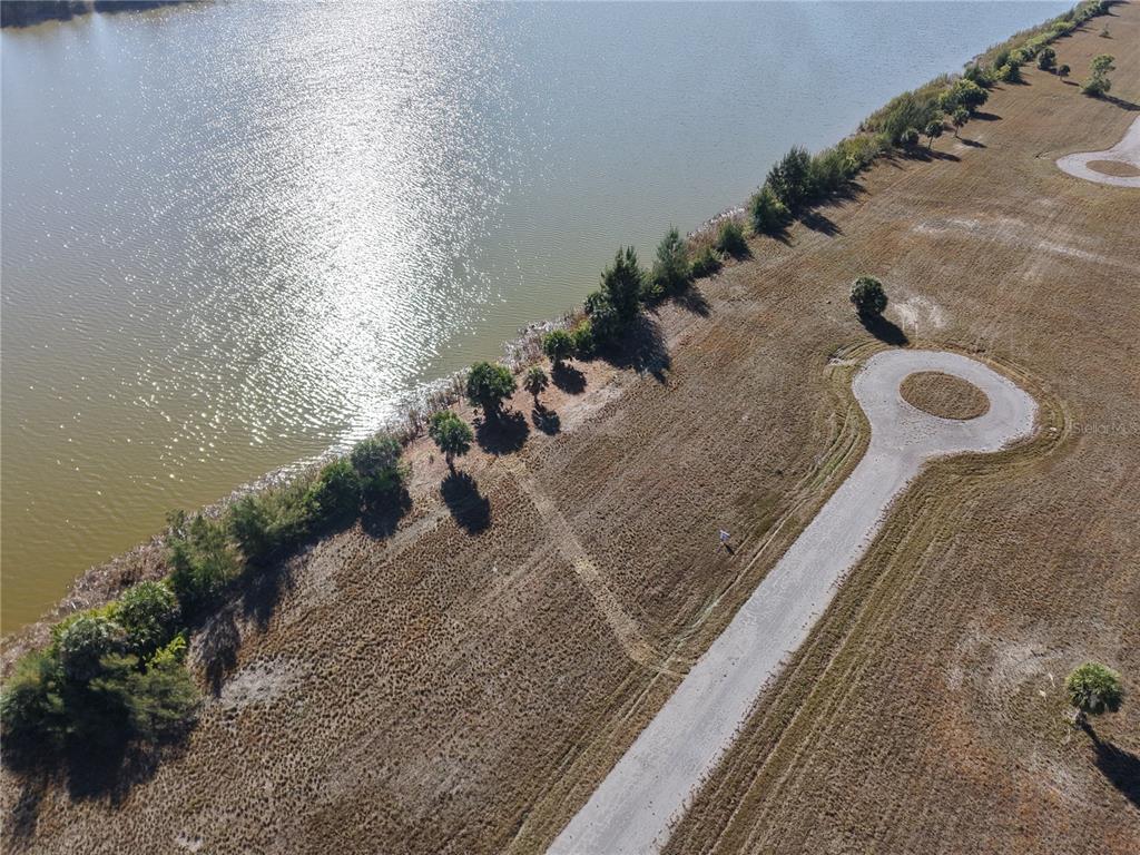 An aerial view shows a vacant lot with a cul-de-sac road bordering a large lake — 8 CHINABERRY WAY, PLACIDA, FL