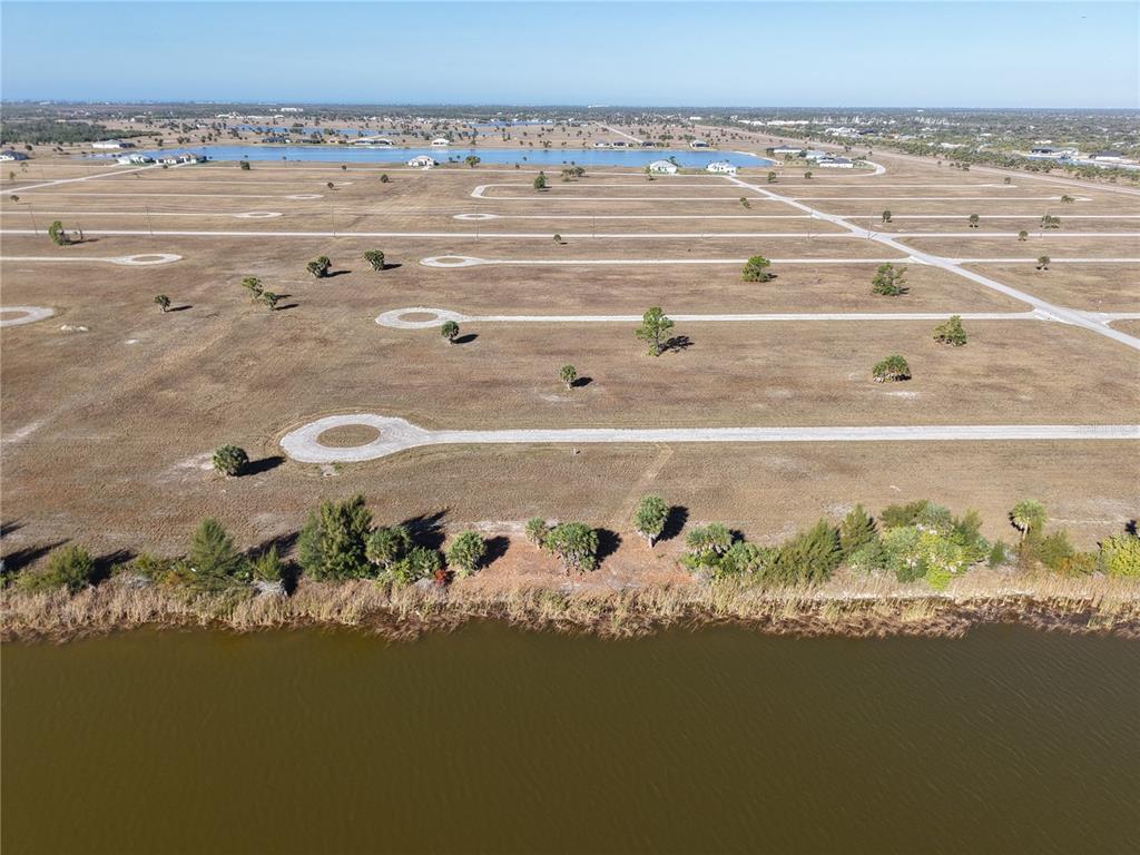 An aerial view shows a large, undeveloped plot of land bordering a lake — 8 CHINABERRY WAY, PLACIDA, FL