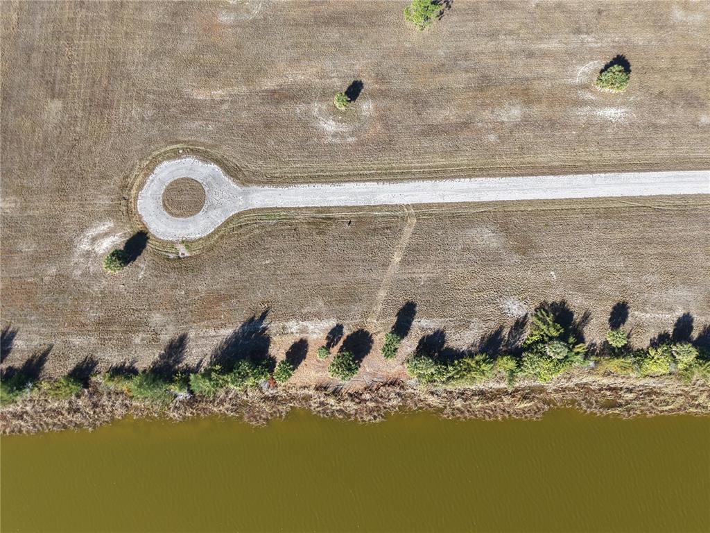 An aerial view shows a gravel cul-de-sac and road situated in a field near water — 8 CHINABERRY WAY, PLACIDA, FL