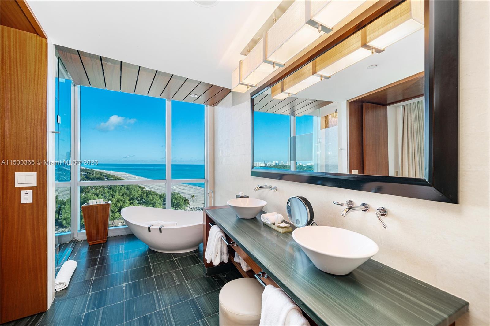 A modern bathroom features a double vanity, a freestanding tub, and floor-to-ceiling ocean views — 10295 Collins Ave # 1216, Bal Harbour FL 33154, BAL HARBOUR, FL