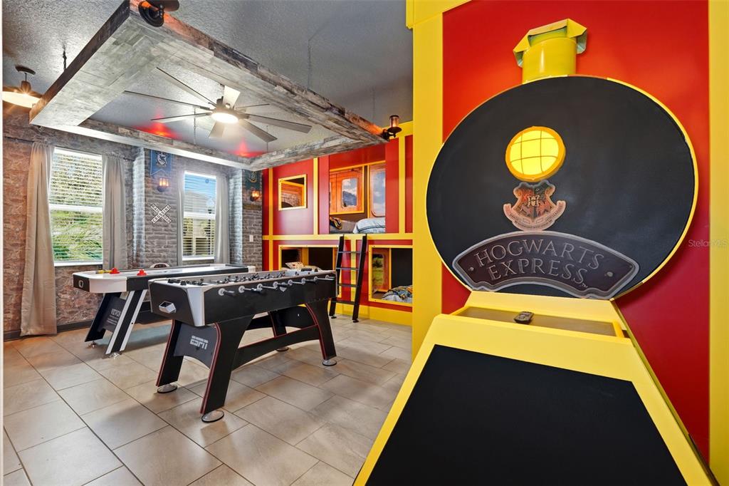 A themed game room features a Hogwarts Express train facade, bunk beds, and game tables — 690 DROP SHOT DRIVE, DAVENPORT, FL