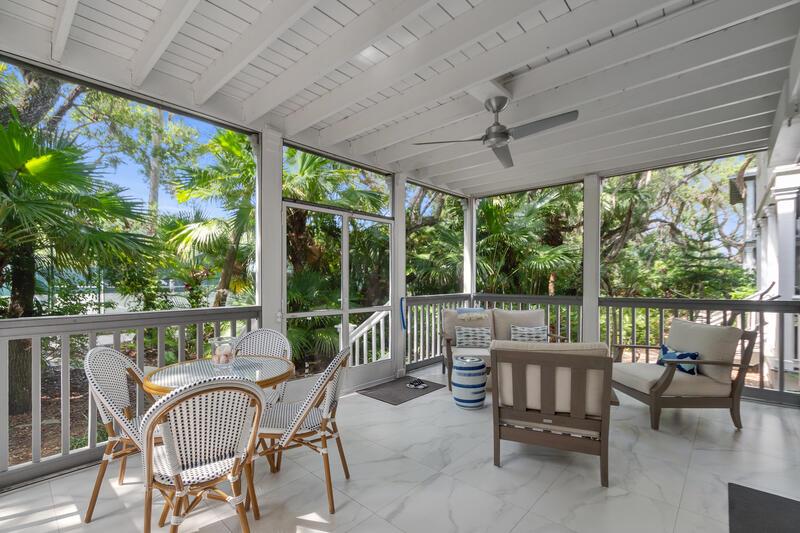 A screened-in porch features white marble-look tile flooring, a ceiling fan, and outdoor furniture — VERO BEACH, FL