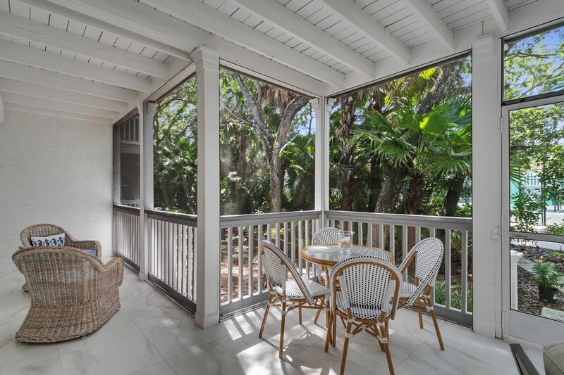 A screened-in porch features white tile flooring, a wicker chair, and a small dining set — VERO BEACH, FL