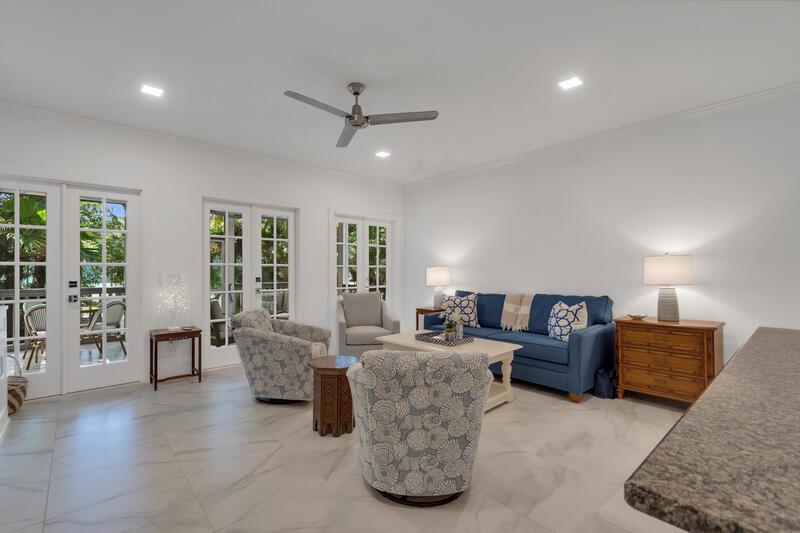 A living room features a blue sofa, patterned armchairs, tile flooring, and glass-paned doors — VERO BEACH, FL