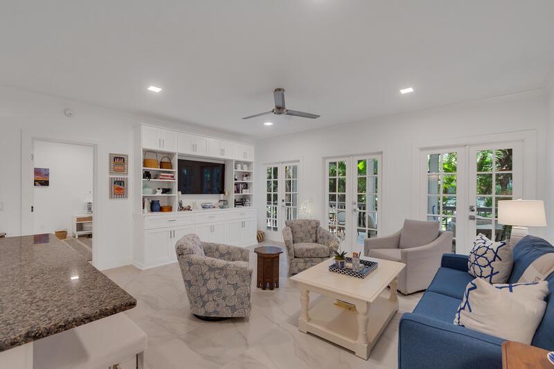A bright living room features white built-in cabinetry, a blue sofa, and glass patio doors — VERO BEACH, FL