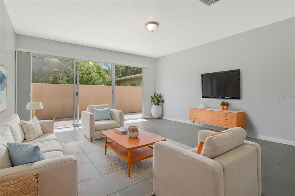 A living room features light-colored furniture, a wooden coffee table, and a sliding glass door — 2284 OAK NECK ROAD UNIT F, CLEARWATER, FL