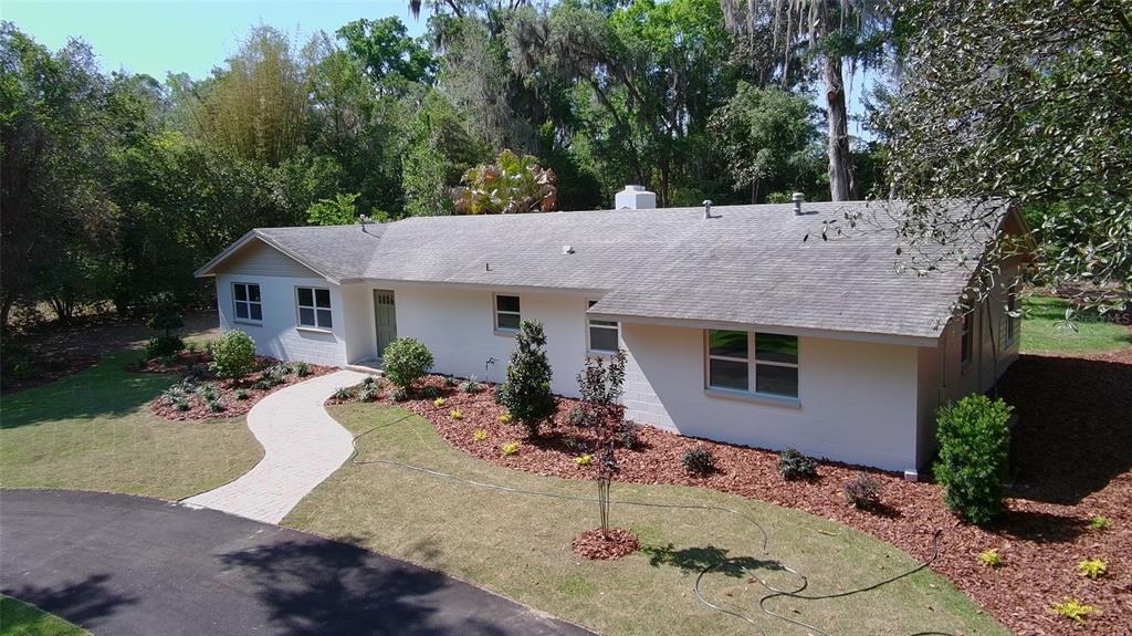 An exterior view of a white, single-story ranch-style house with a paved walkway and landscaping — 4890 NW 20TH PLACE, GAINESVILLE, FL