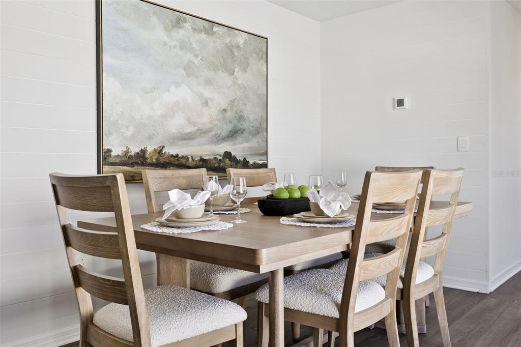A dining room features a wooden table with chairs, white shiplap walls, and landscape art — 3999 LIMEKLIN FALLS LOOP, DAVENPORT, FL