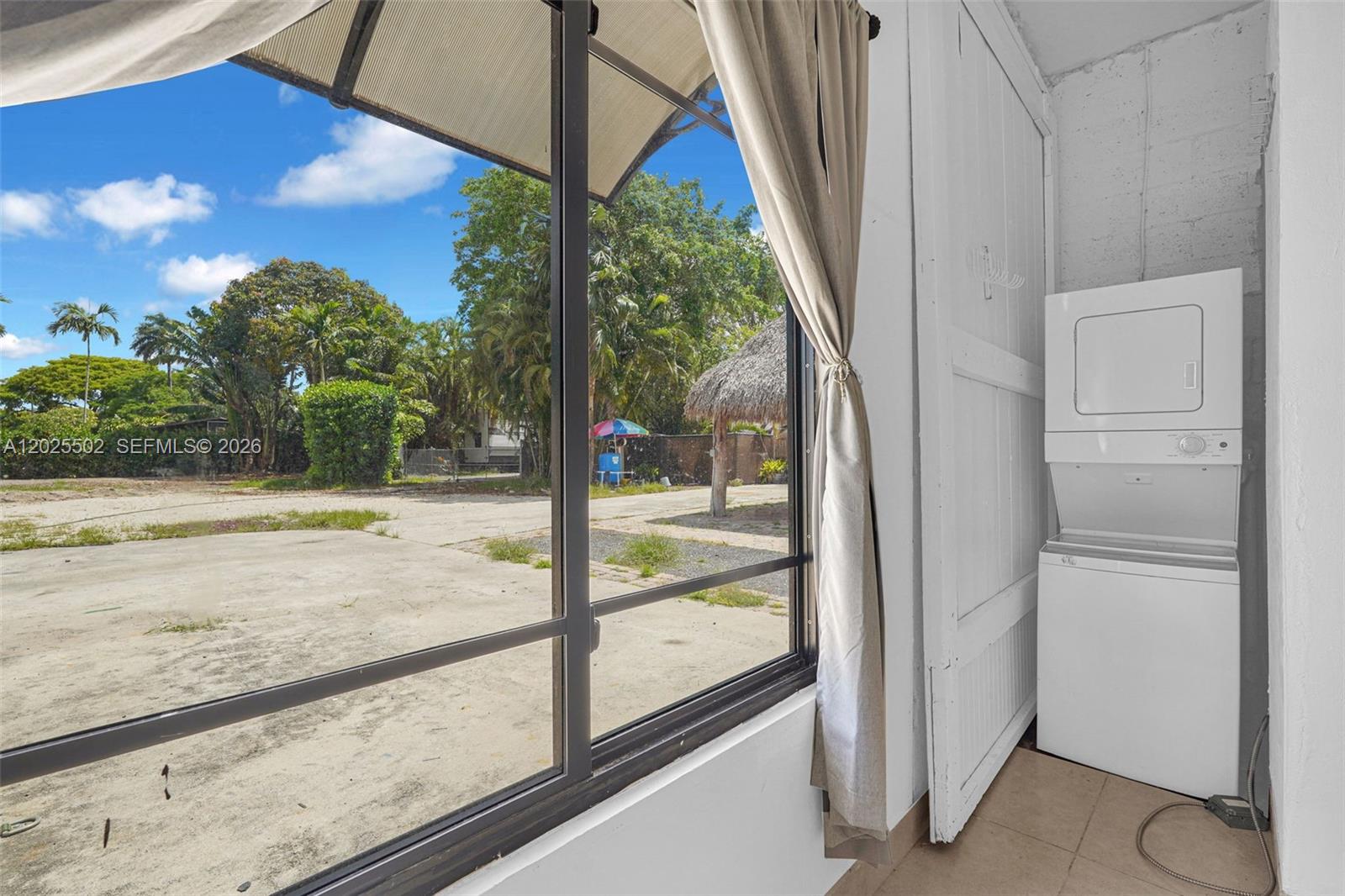 A laundry area with a stacked washer and dryer overlooks a paved outdoor space — 14500 NE 2nd Ave # 2, Miami FL 33161, MIAMI, FL