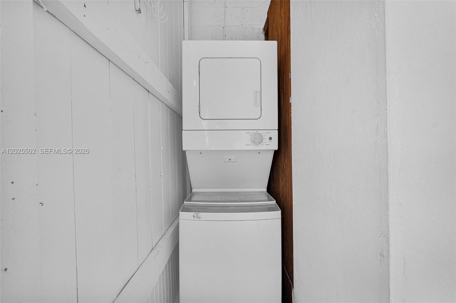 A white stacked washer and dryer unit sits in a corner against white walls — 14500 NE 2nd Ave # 2, Miami FL 33161, MIAMI, FL