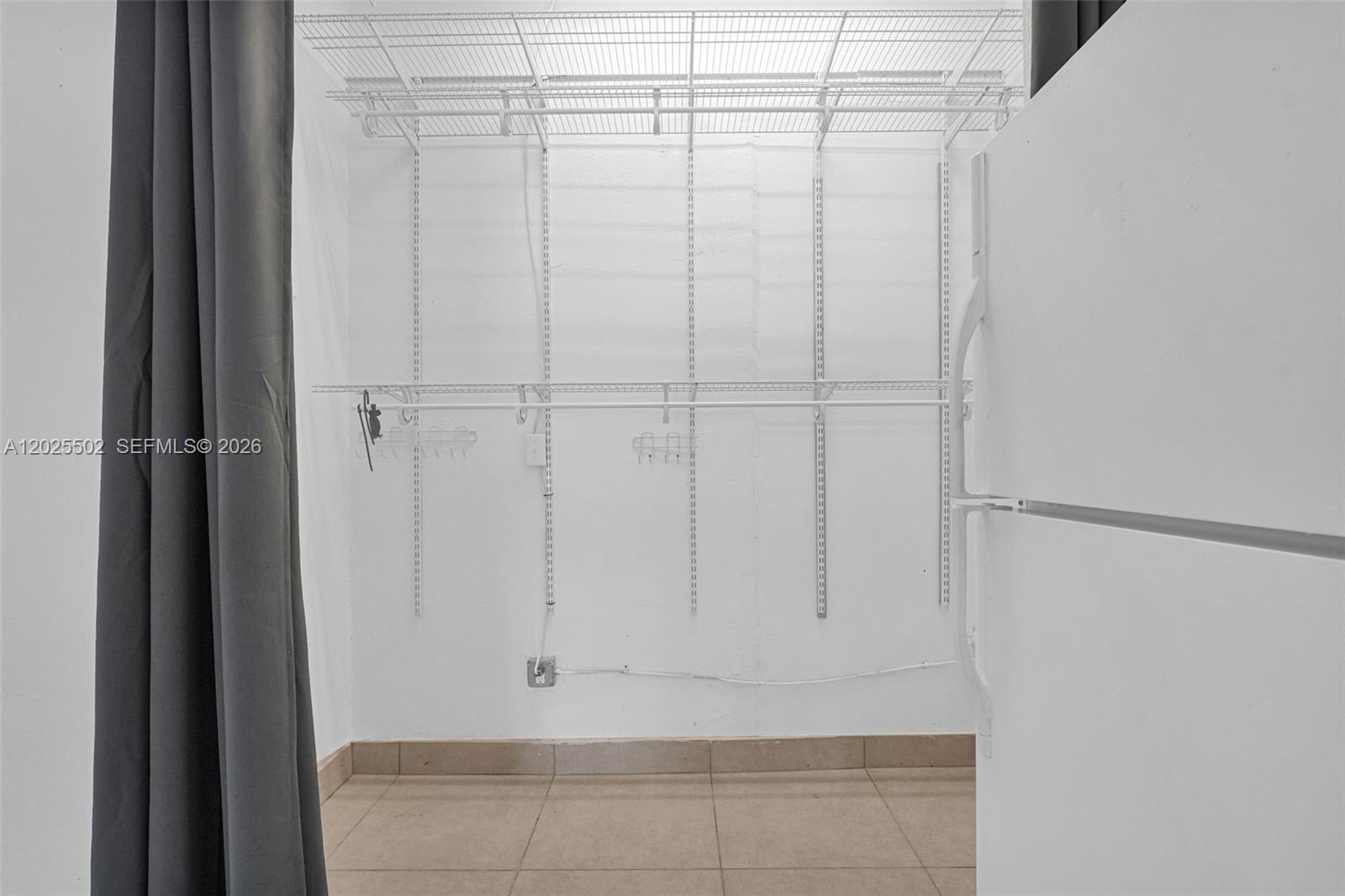 A walk-in closet features white wire shelving, tiled flooring, and a grey curtain entrance — 14500 NE 2nd Ave # 2, Miami FL 33161, MIAMI, FL