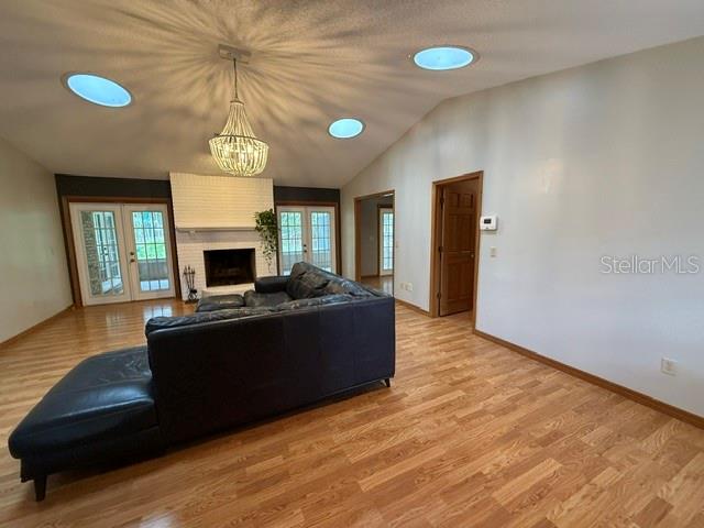 A living room features a dark sectional sofa, a white brick fireplace, and vaulted ceilings — 1990 LARCHMONT DRIVE, DELAND, FL
