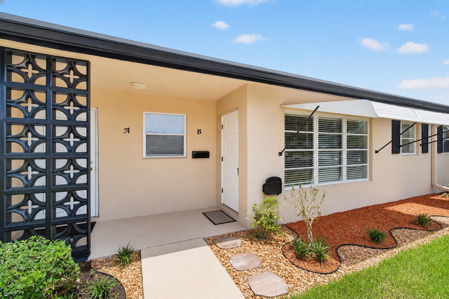 The exterior of a duplex features two white doors labeled A and B with decorative screens — 1007 South Drive, Delray Beach FL 33445, DELRAY BEACH, FL