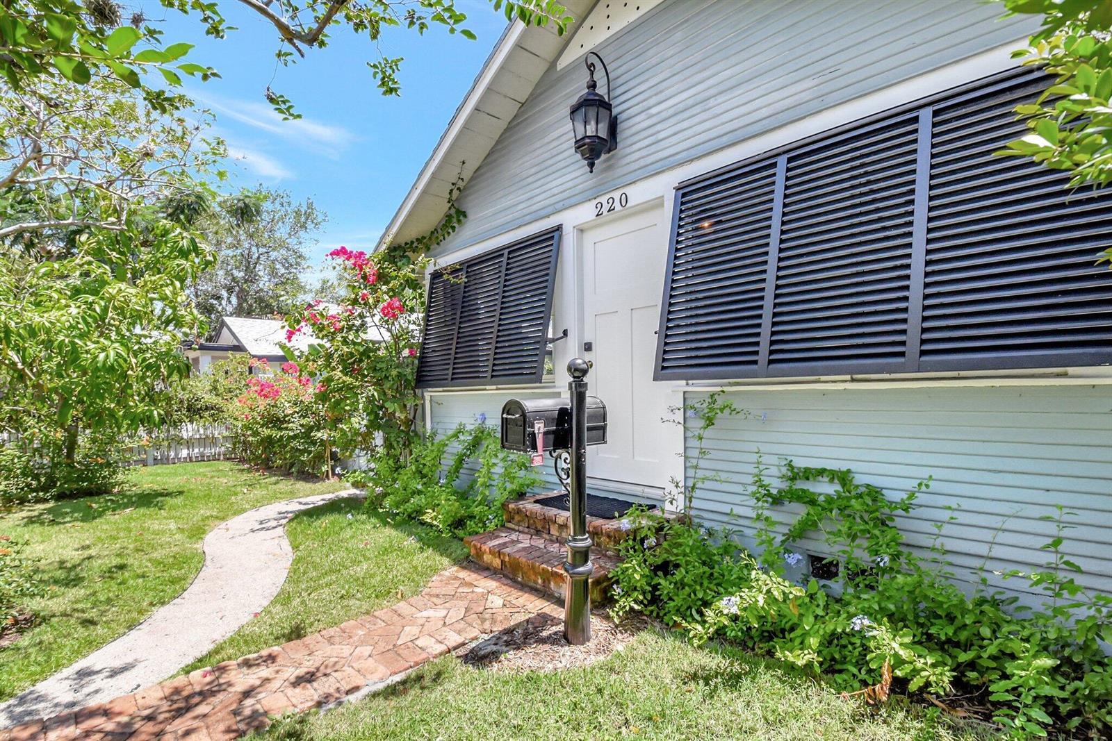 A light blue house exterior features black shutters, a white front door, and a brick walkway — 220 S L Street, FL 33460, FL