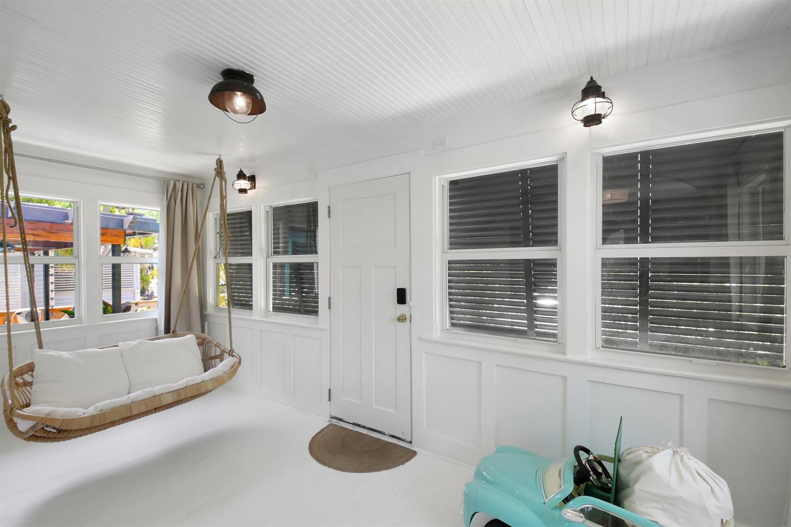 A bright sunroom features white walls, a hanging wicker chair, and a toy car — 220 S L Street, FL 33460, FL