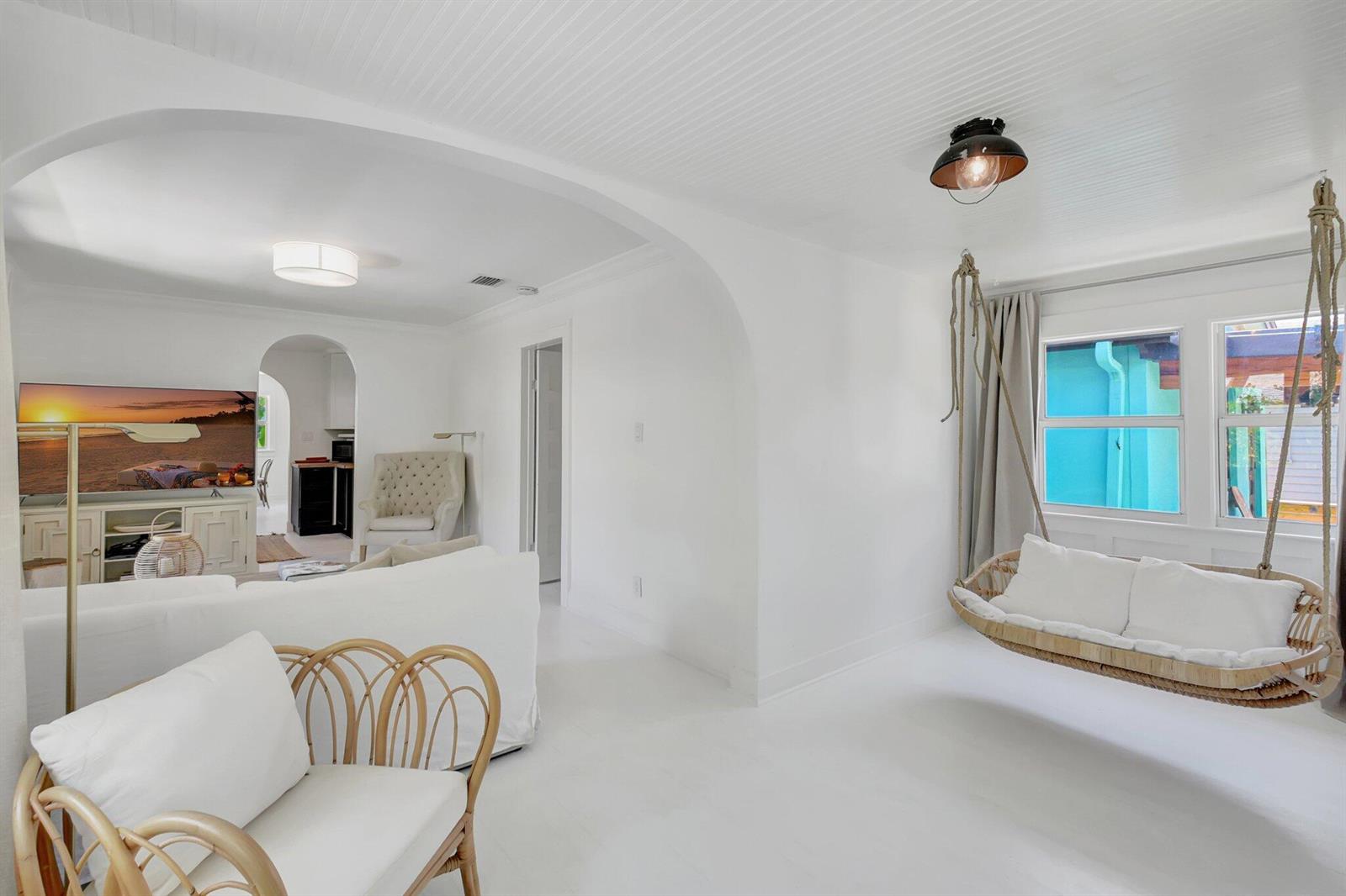A bright living room features white walls, a hanging rattan swing, and an arched entryway — 220 S L Street, FL 33460, FL