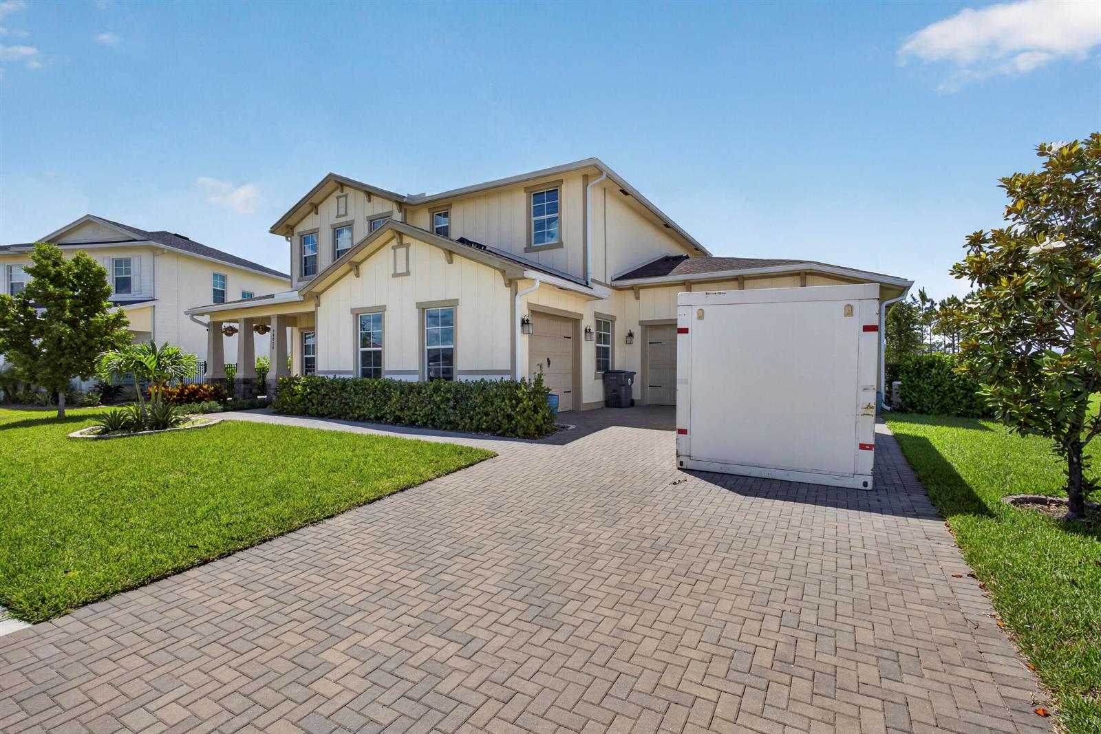 A two-story house with light-colored siding and a paved driveway featuring a large storage container — 18974 Tackle Box Trail, Loxahatchee FL 33470, LOXAHATCHEE, FL
