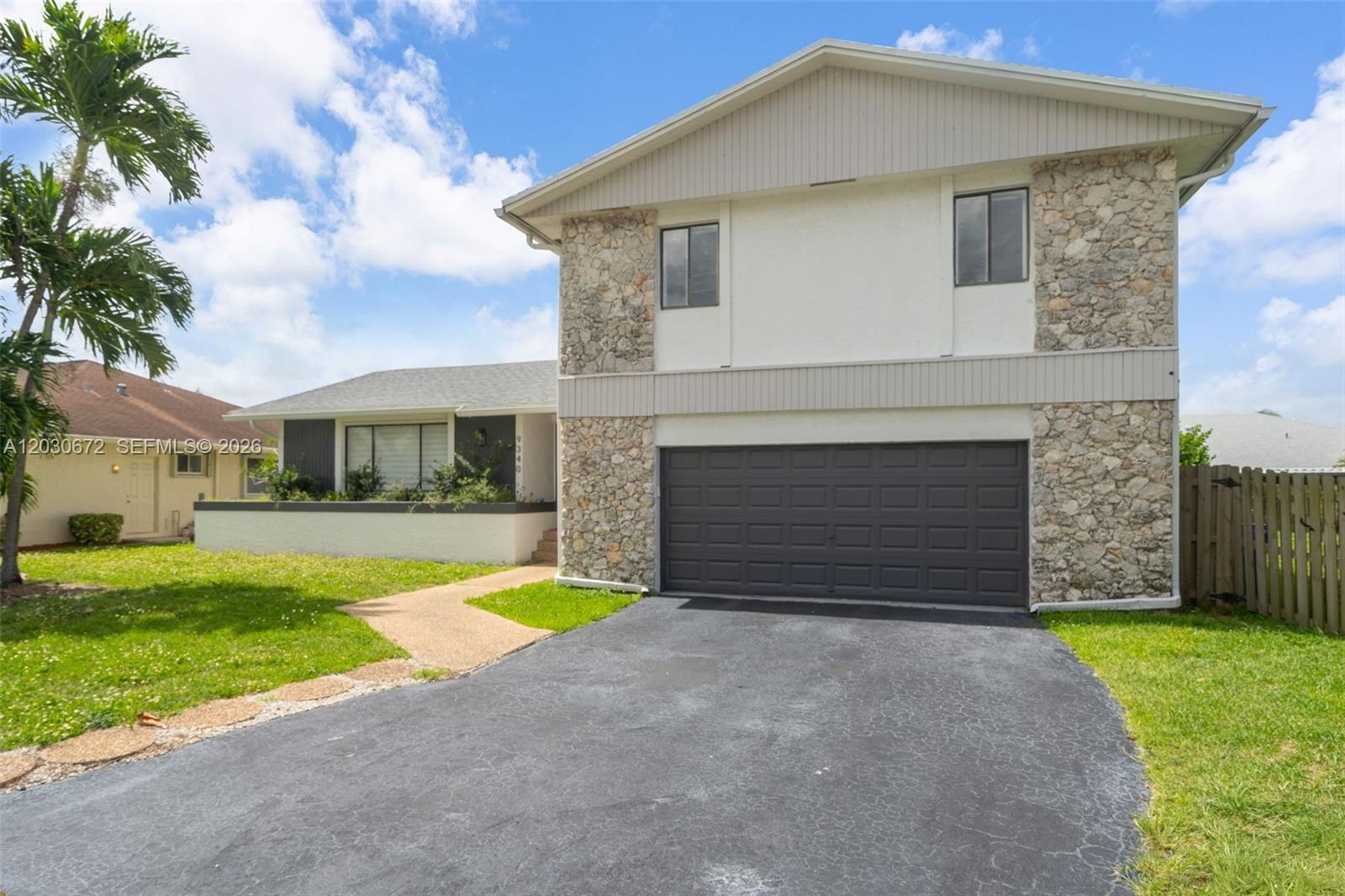 A two-story house features a stone facade, a dark garage door, and a front lawn — 9340 NW 32nd St, Sunrise FL 33351, SUNRISE, FL
