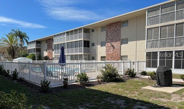 An exterior view of a multi-story apartment building with a swimming pool and fenced patio — 3751 S SCHOOL AVENUE UNIT 29, SARASOTA, FL