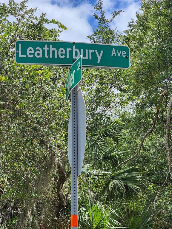 A street sign for Leatherbury Ave stands against a background of lush green trees — 13397 LEATHERBURY AVENUE, PORT CHARLOTTE, FL
