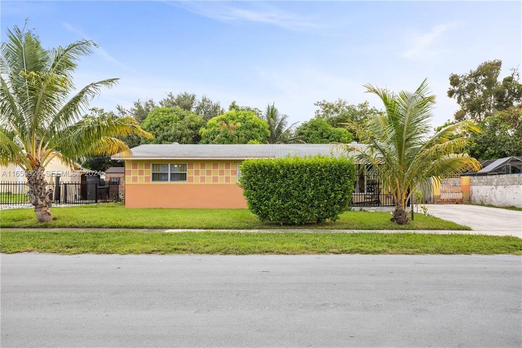 A single-story house with an orange and yellow exterior sits behind a manicured lawn — 18930 NW 14th Avenue, Miami FL 33169, MIAMI, FL