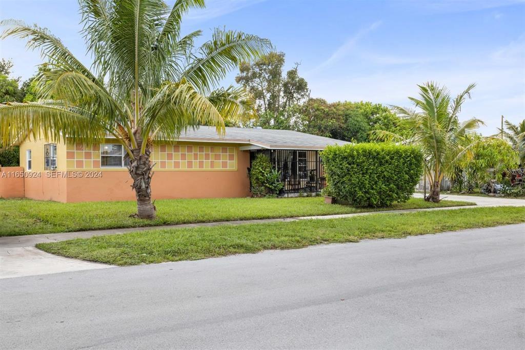 A single-story house with an orange exterior, a tiled facade, and palm trees in front — 18930 NW 14th Avenue, Miami FL 33169, MIAMI, FL