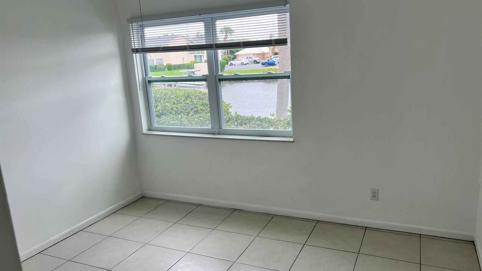 An empty room with white walls, tiled flooring, and a window overlooking a canal — 1860 Robalo Drive # 104, Vero Beach FL 32960, VERO BEACH, FL