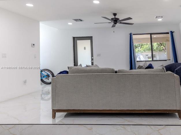 A living room features a light gray sofa, white walls, and white tile flooring — 666 NE 164th Ter, Miami FL 33162, MIAMI, FL