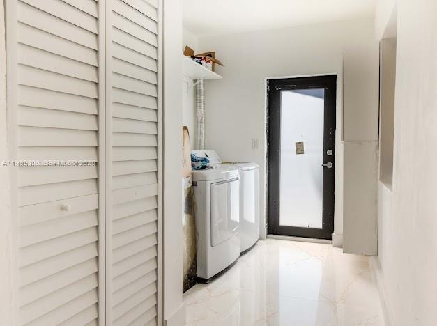 A laundry room with white louvered closet doors, a washer and dryer, and tile flooring — 666 NE 164th Ter, Miami FL 33162, MIAMI, FL