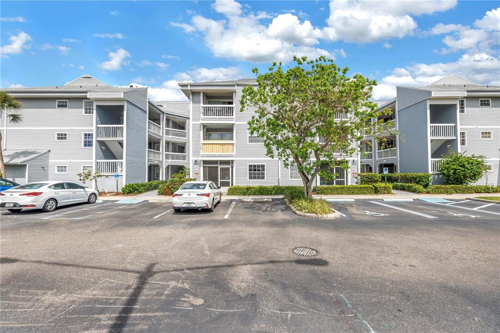 A multi-story apartment building with gray siding features balconies and a parking lot out front — 6924 STONES THROW CIRCLE N UNIT 8103, ST PETERSBURG, FL