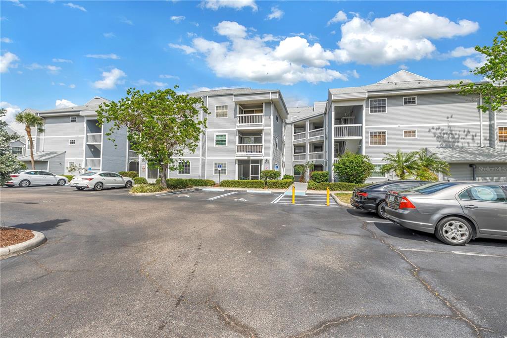 A multi-story apartment building with gray siding and a parking lot in the foreground — 6924 STONES THROW CIRCLE N UNIT 8103, ST PETERSBURG, FL