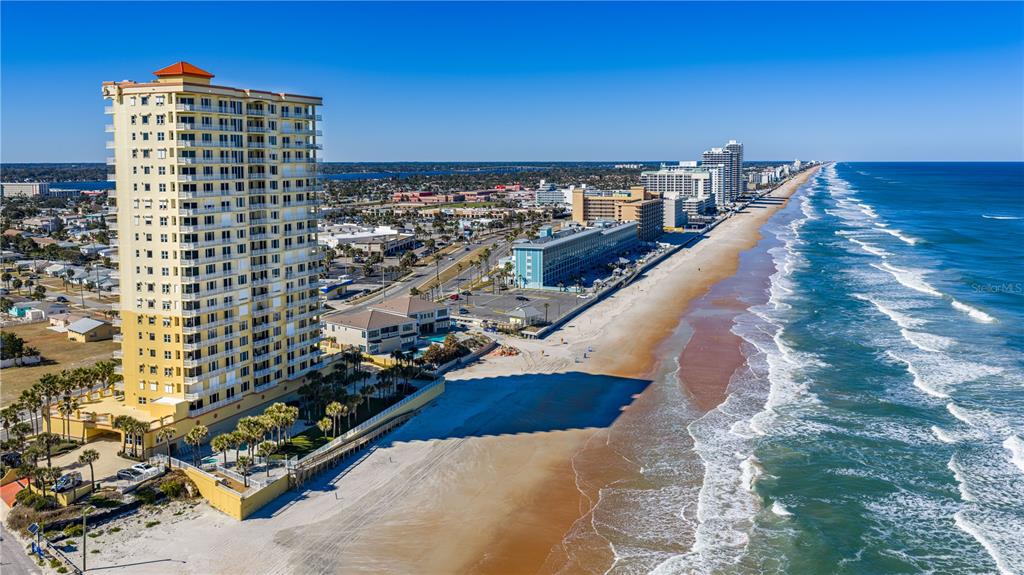 An aerial view of a tall beachfront condominium tower overlooking the Atlantic Ocean and coastline — 2300 N ATLANTIC AVENUE UNIT 101, DAYTONA BEACH, FL