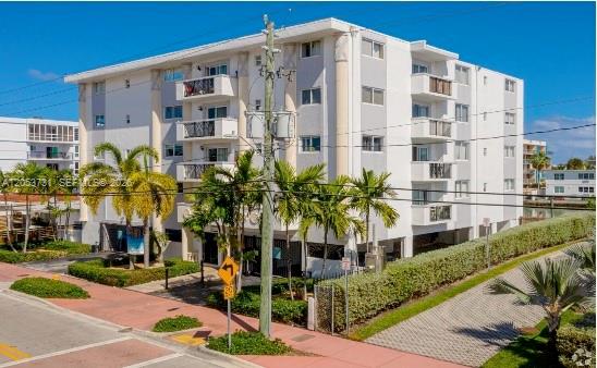 A multi-story white apartment building with balconies and palm trees sits next to a sidewalk — 8101 Crespi Blvd # 404, Miami Beach FL 33141, MIAMI BEACH, FL
