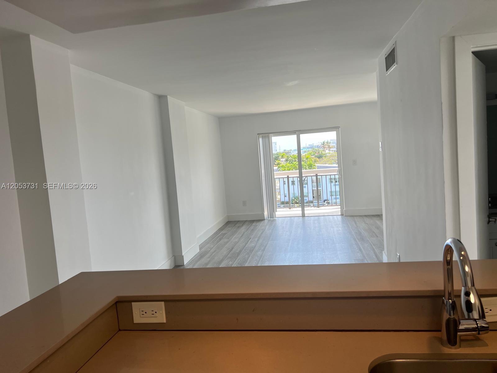 A view from a kitchen counter looking toward a living area with a balcony door — 8101 Crespi Blvd # 404, Miami Beach FL 33141, MIAMI BEACH, FL