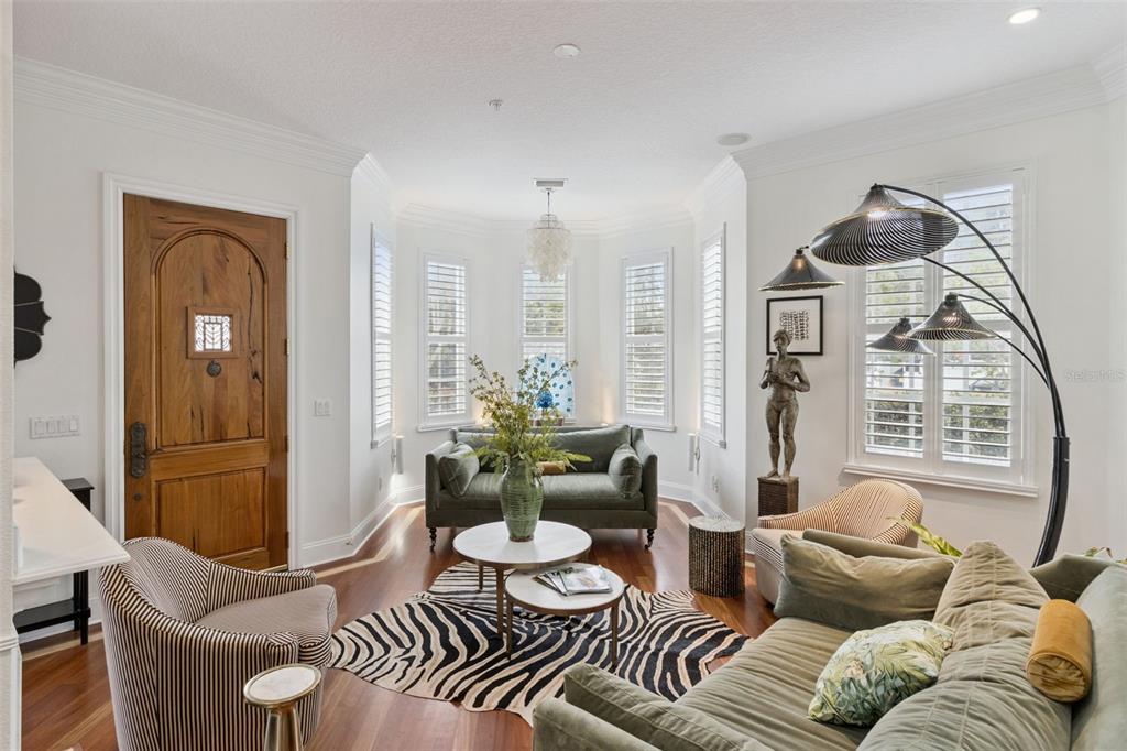 A living room features a wooden door, a zebra-print rug, and two green sofas — 2402 VICTORIA GARDENS LANE, TAMPA, FL