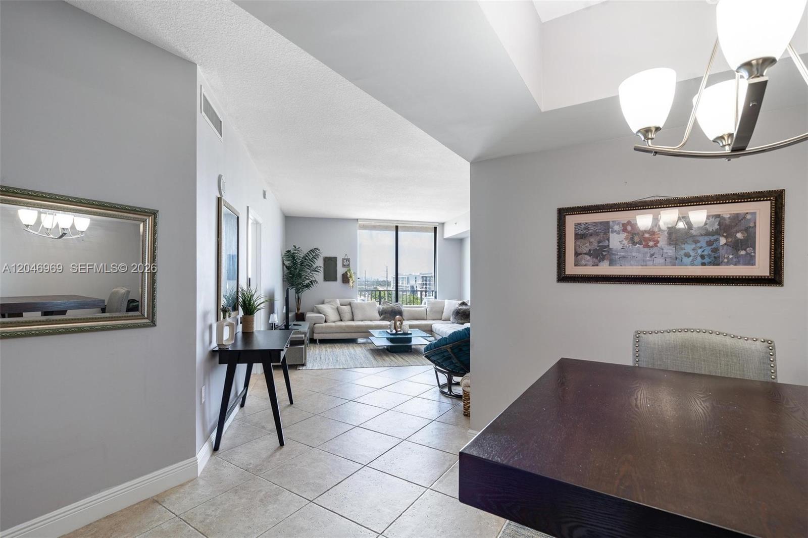 A dining area opens into a living room with tile floors and a balcony view — 140 S Dixie Hwy # 609, Hollywood FL 33020, HOLLYWOOD, FL